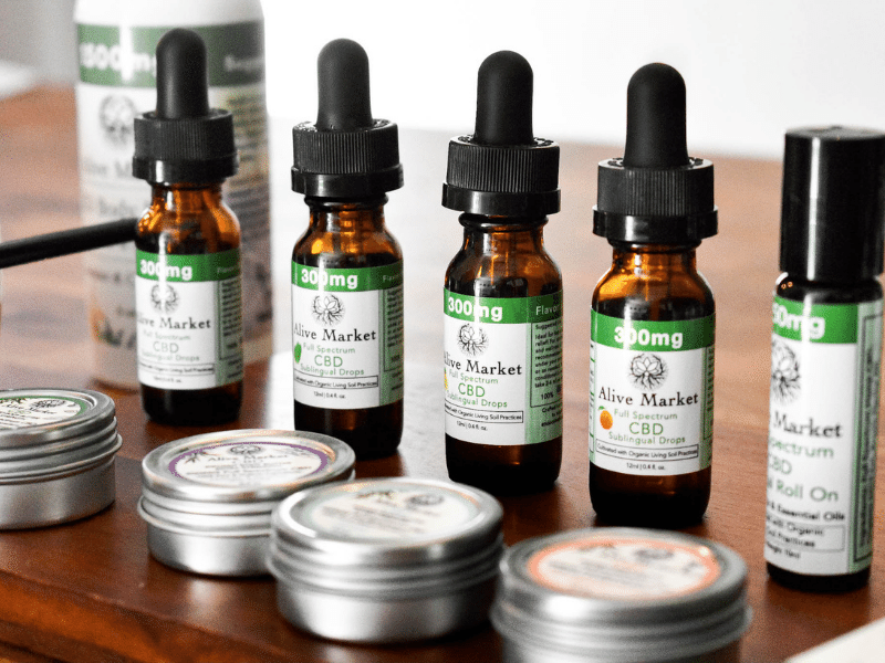 a wide range of CBD products on a table: CBD body butter, CBD oil, CBD roll on.